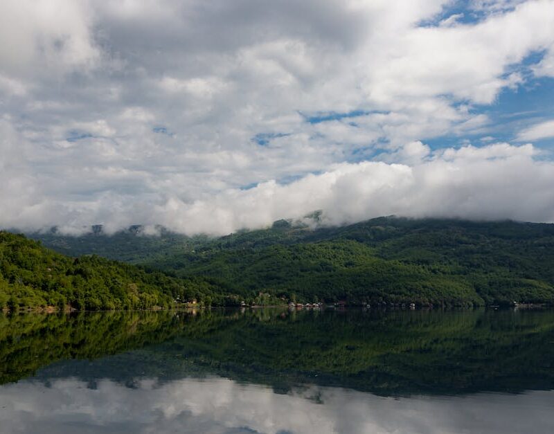 Lake Reflections - Peaceful lake with lush green hills and clouds r #25391558