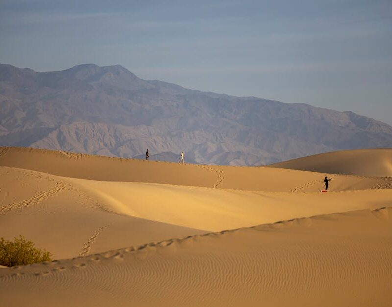 Desert Wilderness - Three hikers traverse the golden sands against a #28639382