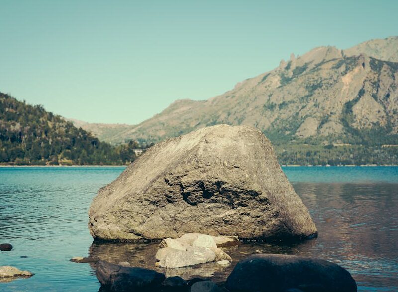 Lake Reflections - Rock in serene lake set against a majestic mount #31717345
