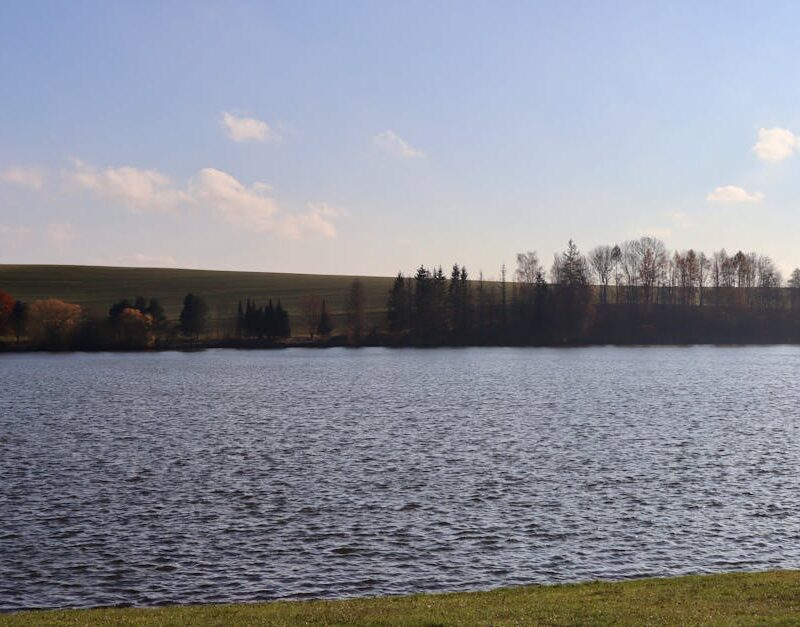 Lake Reflections - Serene lake view with trees and rolling hills in #34639701