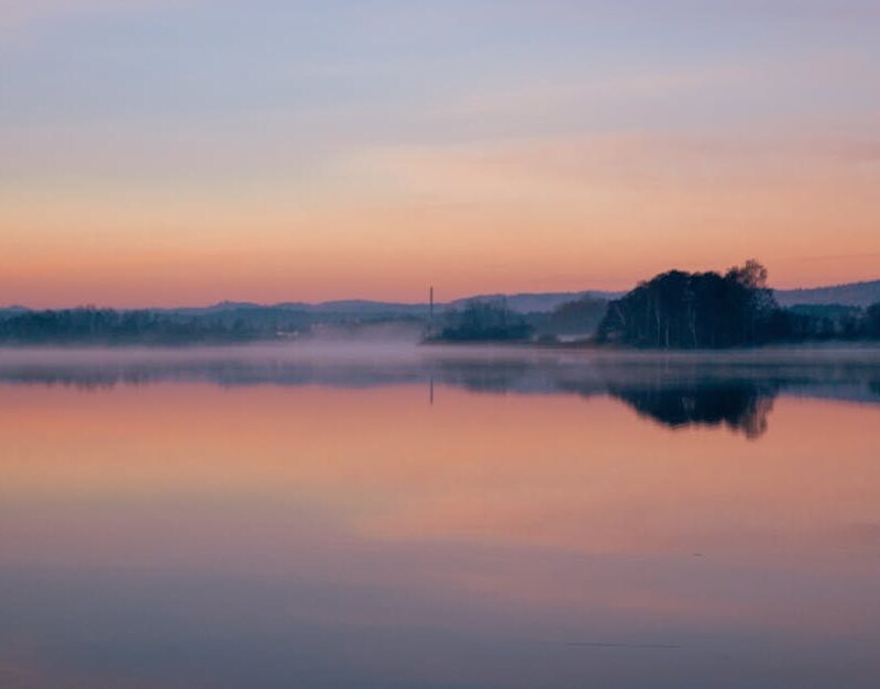 Lake Reflections - Peaceful scene of a misty lake reflecting the su #34670467