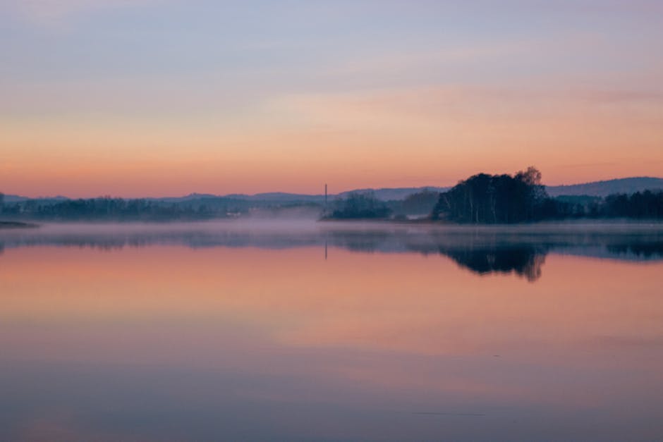 Lake Reflections - Peaceful scene of a misty lake reflecting the su #34670467