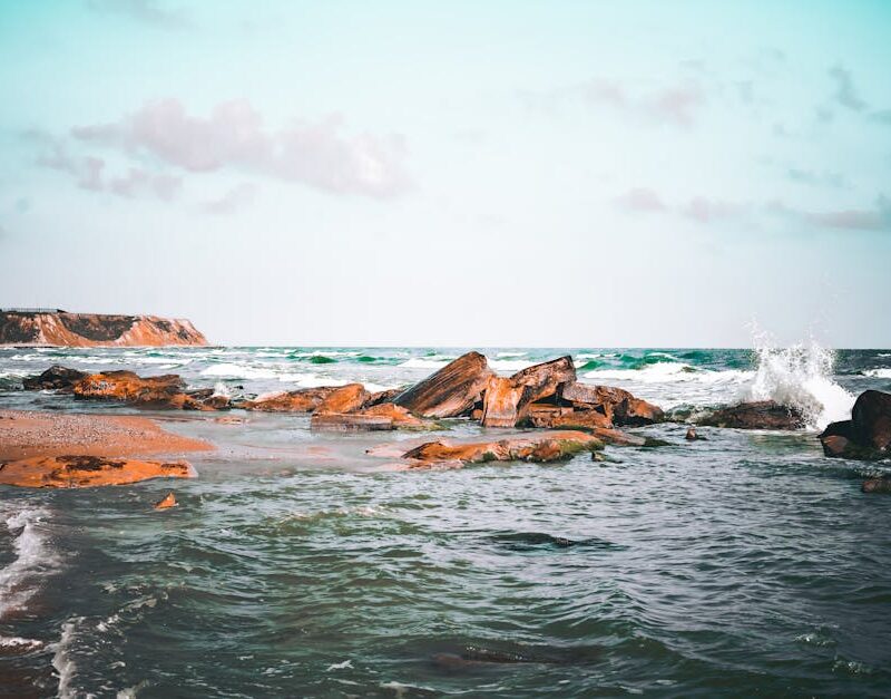 Beach Scenery - A tranquil beach scene featuring a rocky shoreli #7469959